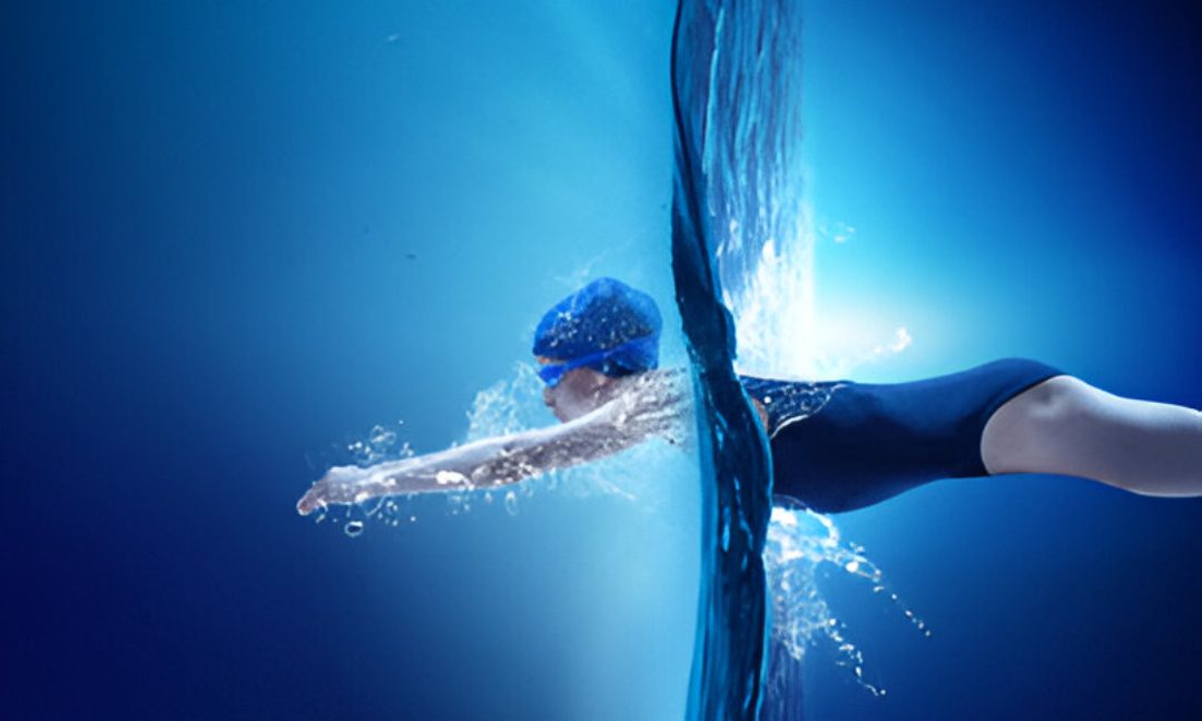 Swimmer diving underwater in blue light.