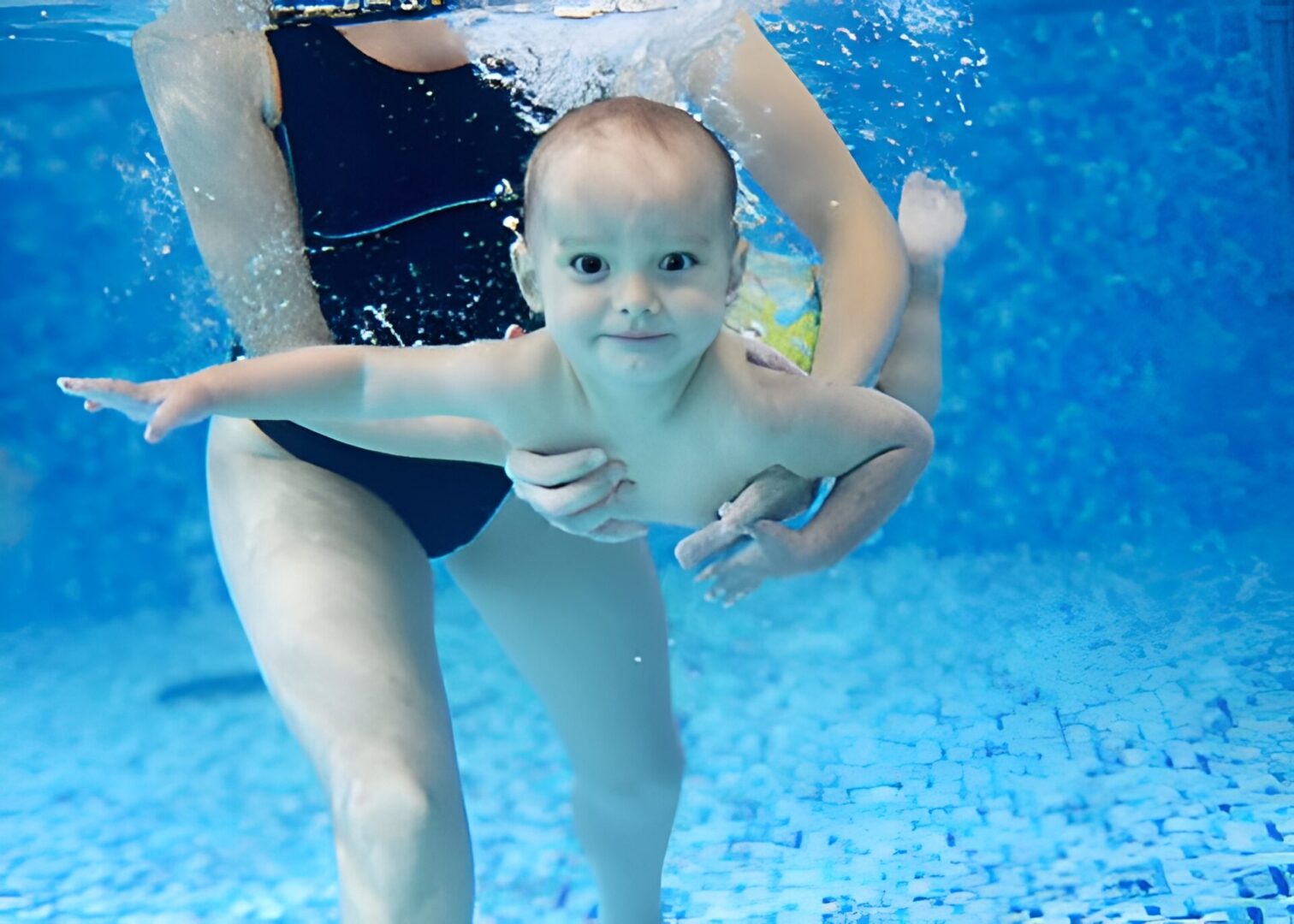 Baby swimming with adult in pool.